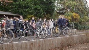 Gruppe mit Jugendlichen und Erwachsenen. Davor sind zahlreiche Fahrräder geparkt. 