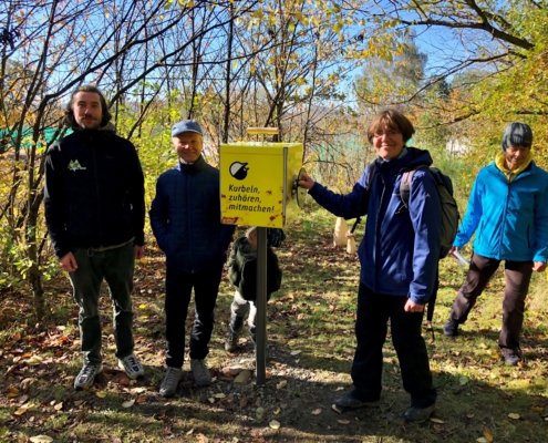 Personen im Wald vor einer Station des Naturerlebnispfades