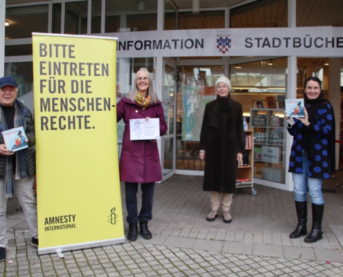 Vor dem Rathaus Personen mit Transparent von AMNESTY