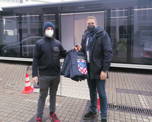 Zwei Personen für dem Impfbus auf dem Rathausplatz mit Geschenktüten