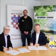 Zwei Personen - Brigitte Kohlhaas und Bürgermeister Otto Neuhoff, sitzend und eine Person - Linus Steinbach - stehend mit Werbetafel für naturpark Siebengebirge