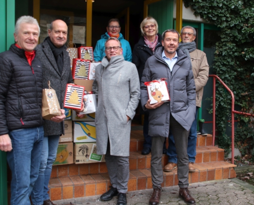 Vor der Tür der Tafel mit Weihnachtstüten ehrenamtliche Tafelmitarbeitende und Vertreter von Sackmarie e. V.