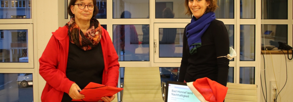 Zwei Personen und im Vordergrund ein Laptop mit Weihnachtsmütze als Symbol für die Zoom-Konferenz