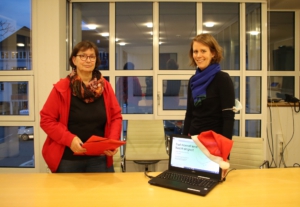 Zwei Personen und im Vordergrund ein Laptop mit Weihnachtsmütze als Symbol für die Zoom-Konferenz